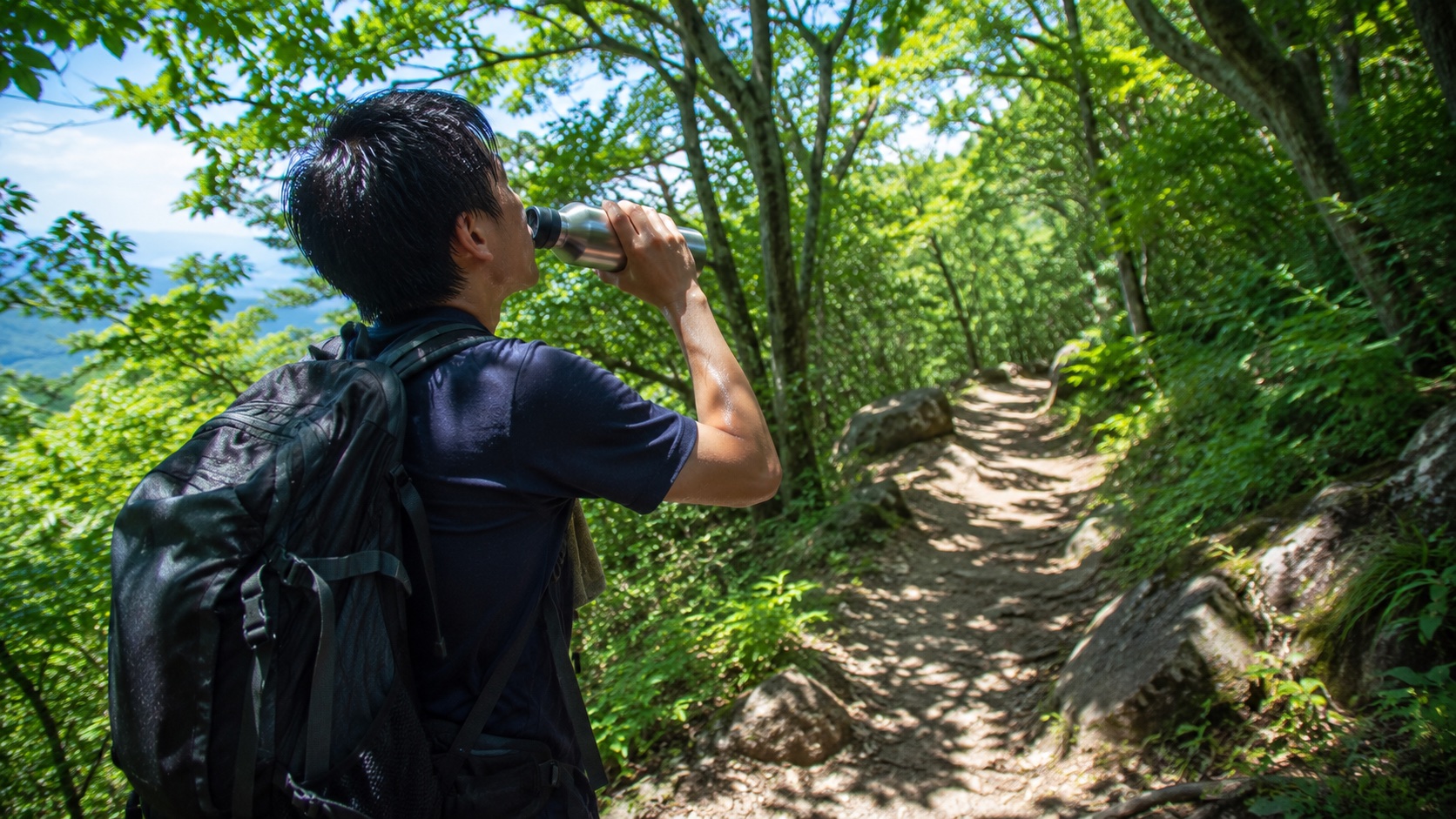 夏の登山道で水筒から水を飲む登山者